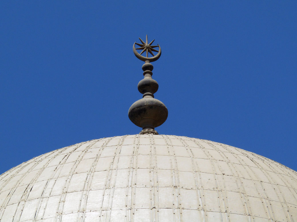 The crescent moon and star, symbol of Islam, sits on top of one of the white domes.