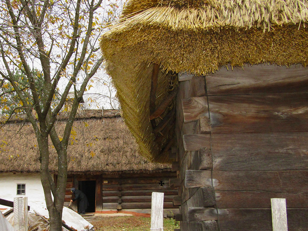 A caretaker sweeps the front of one of the village homes. This one had a fresh wheat thatched roof.