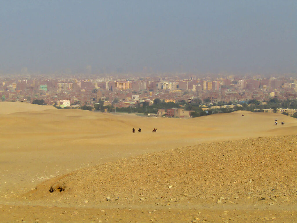 View of desert riders and the city of Cairo in the distance.