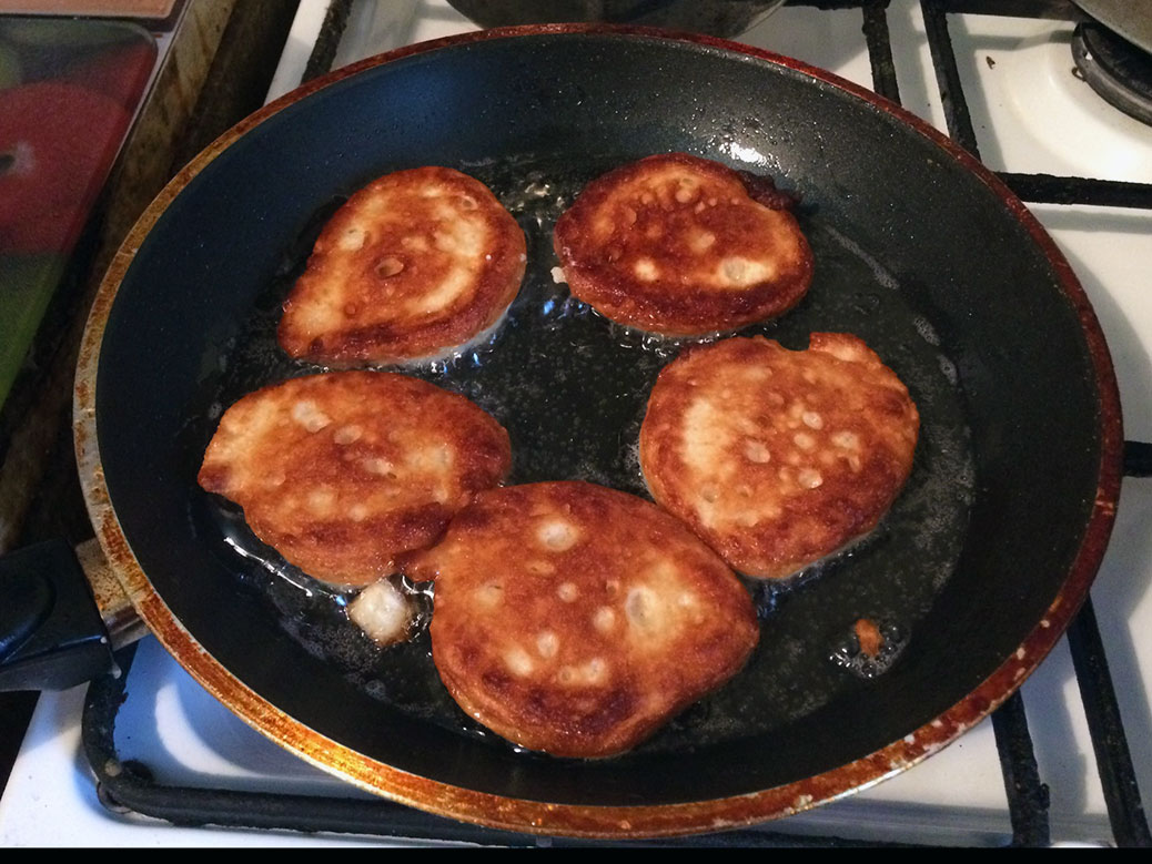 Oladi pancakes browning in the pan; my aunt is not afraid of oil!