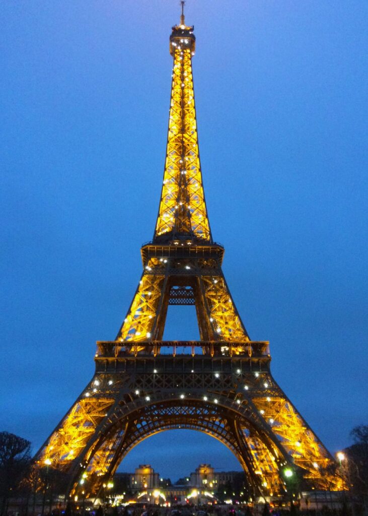 The Eiffel Tower glittering at night as seen from Champ de Mars.